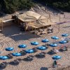 Spiaggia con ombrelloni blu e struttura in legno.