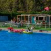 Piscina all'aperto con persone che nuotano e giochi gonfiabili colorati.