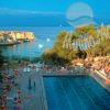 Una piscina all'aperto vicino al mare con ombrelloni e sdraio.