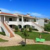 Edifici bianchi a due piani con scale esterne in un giardino ben curato.