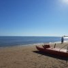 Gommone rosso su spiaggia al tramonto, ciclista lontano.