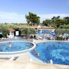 Due piscine all'aperto con bagnanti e ombrelloni blu.