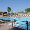 Piscina all'aperto con lettini e ombrelloni gialli e arancioni.