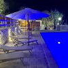 Piscina illuminata di notte con lettini e ombrellone.