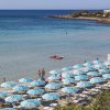 Spiaggia con ombrelloni azzurri e mare calmo.