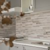 Cucina moderna con mobili grigi, lavello in acciaio e piastrelle grigie.