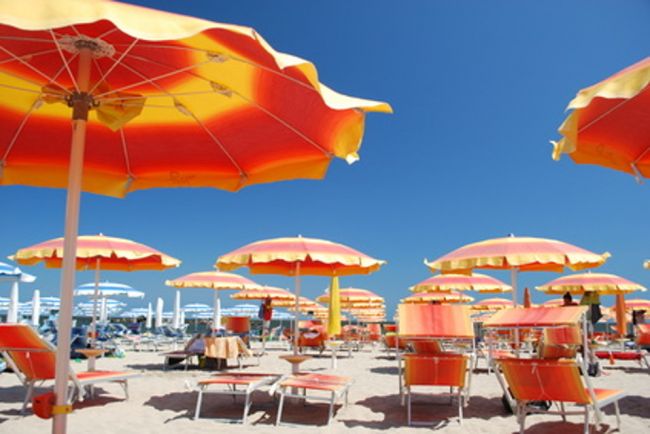 Spiaggia con ombrelloni arancioni e lettini.