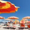 Spiaggia con ombrelloni arancioni e lettini.