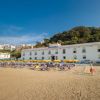Una spiaggia con ombrelloni gialli e un hotel bianco sullo sfondo.
