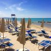 Spiaggia soleggiata con ombrelloni e lettini.