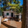 Veranda di una casa bianca nel bosco con lettini e barbecue.