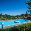 Una piscina all'aperto con ombrelloni blu e bianchi e lettini, circondata da vegetazione.