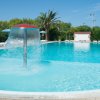 Piscina con fontana e lettini bianchi.